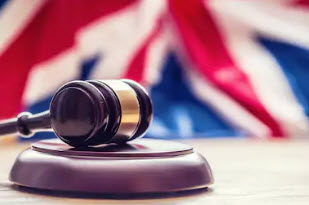 A judge's gavel in front of the UK national flag