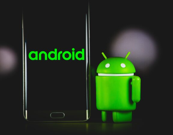 Image of the Android logo beside a smartphone against a black background.