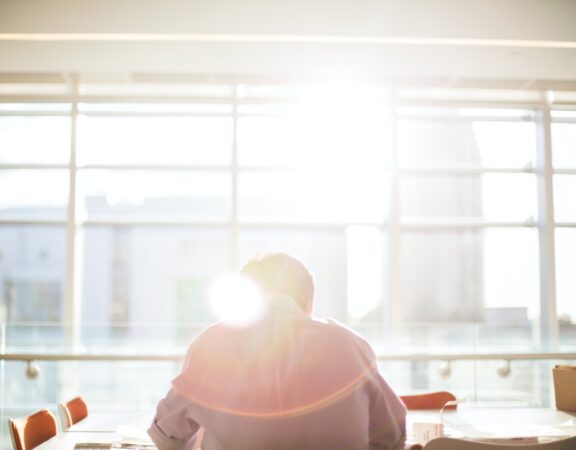 Business person sitting a board room table in front of sunny window