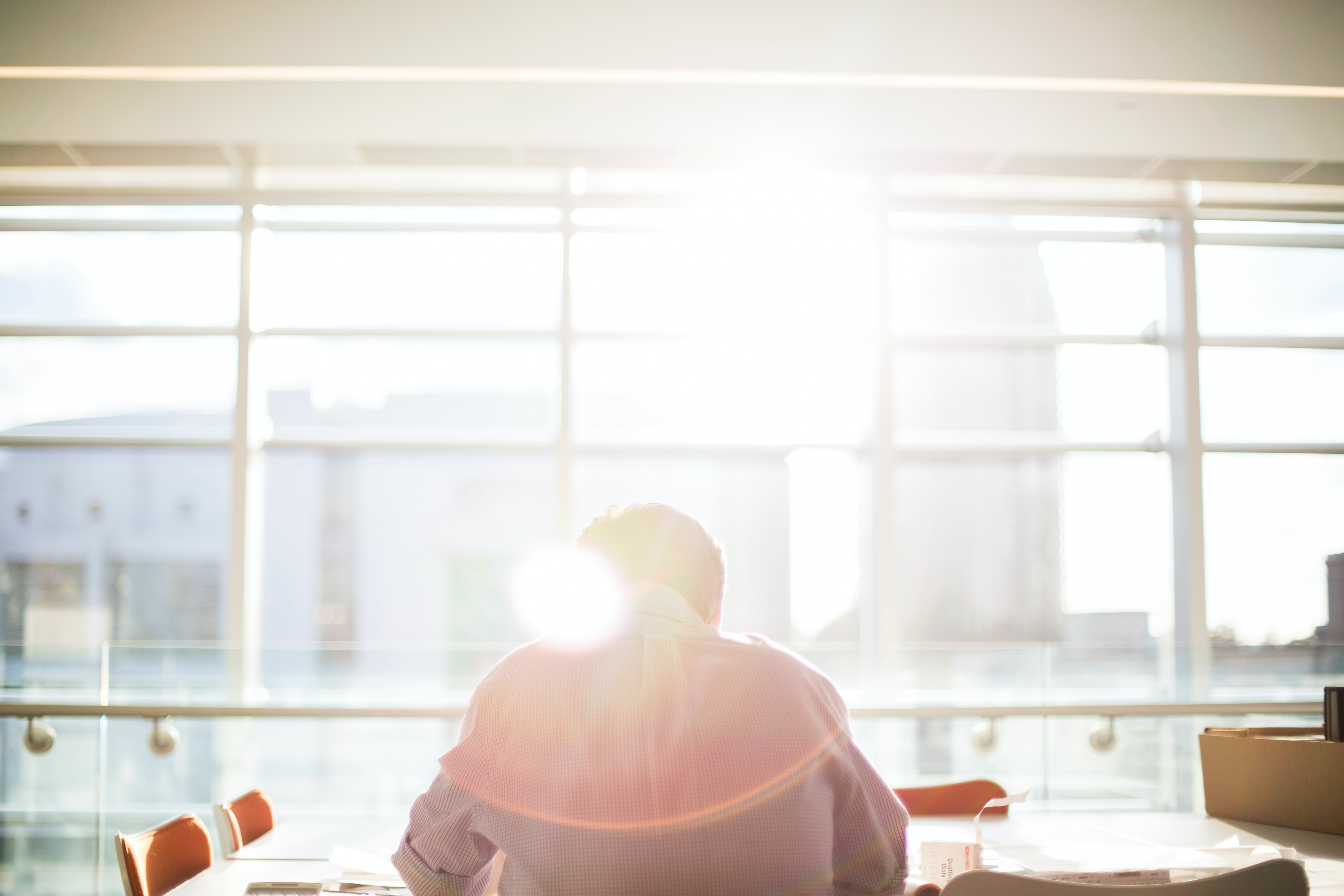 Business person sitting a board room table in front of sunny window