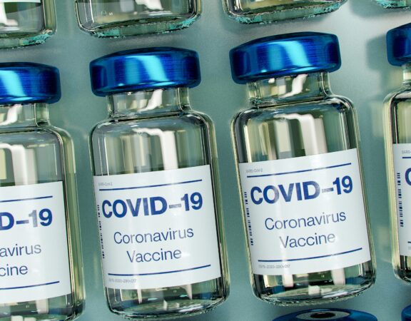 Photograph of a row of glass bottles containing vaccines against COVID-19.