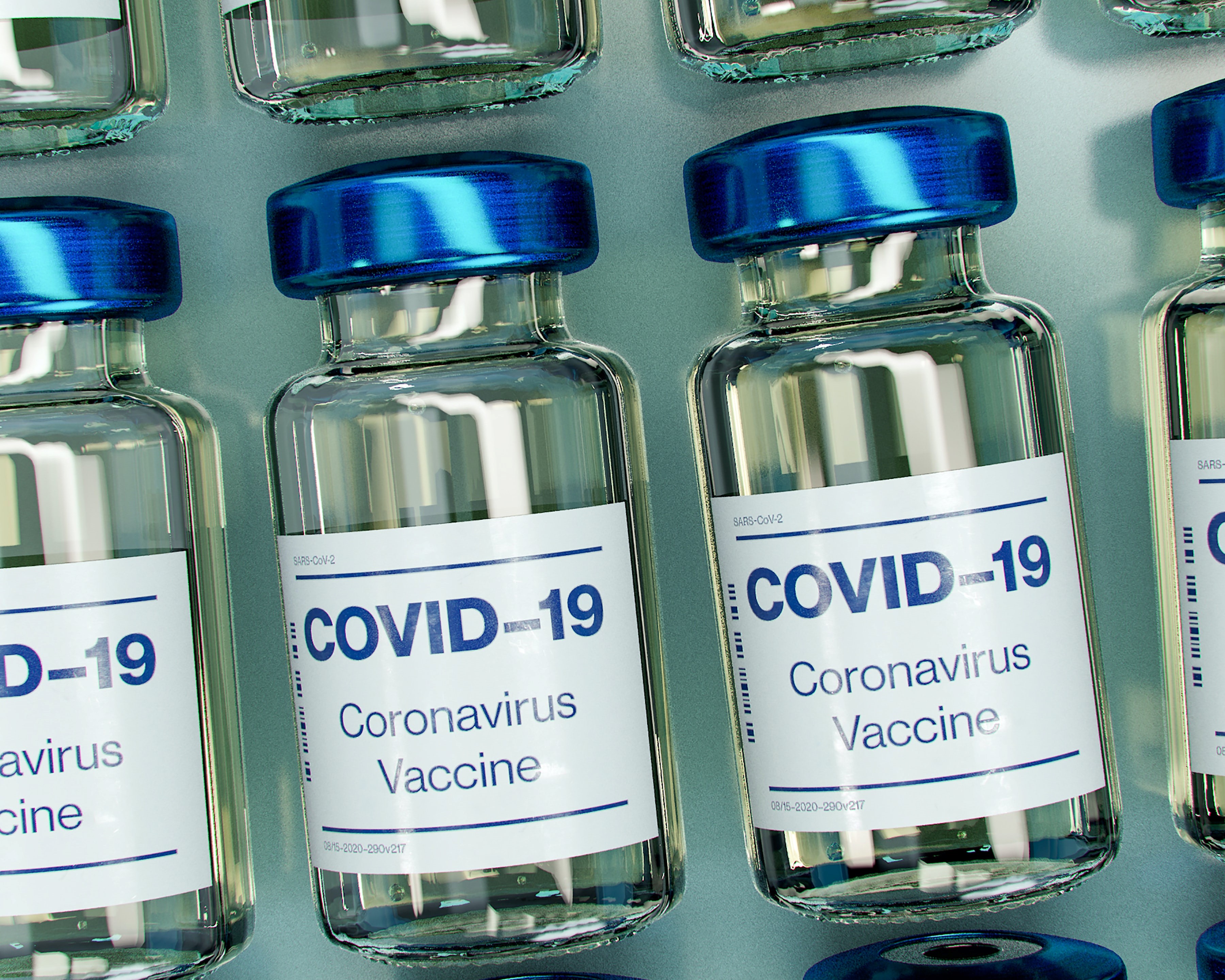 Photograph of a row of glass bottles containing vaccines against COVID-19.