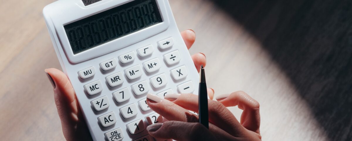 Photograph of a hand holding a calculator and performing financial calculations.