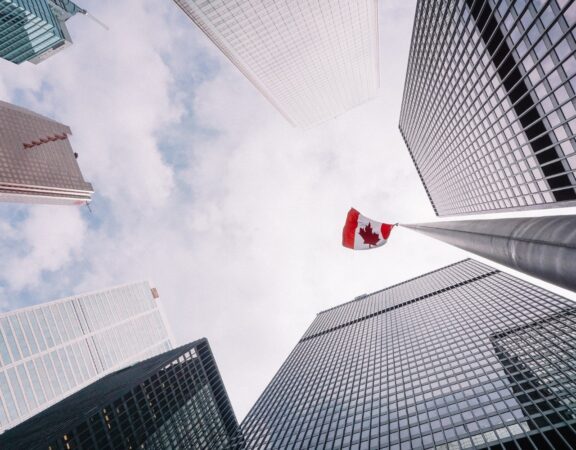 Photograph of Canadian flag waving between skyscrapers in the business district of Toronto