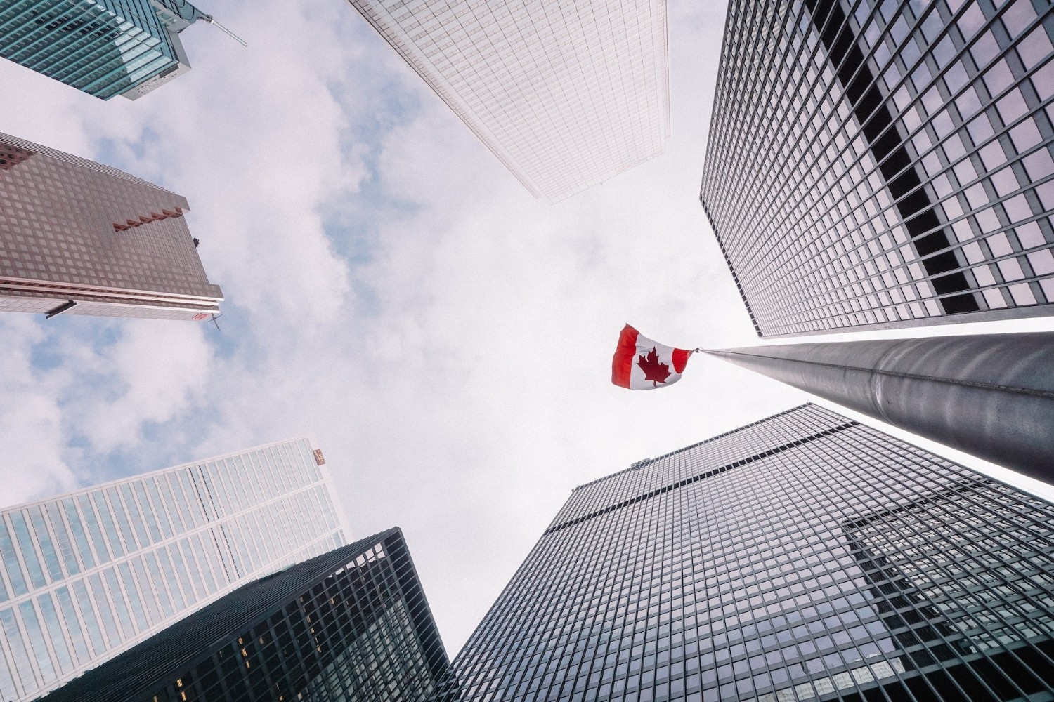 Photograph of Canadian flag waving between skyscrapers in the business district of Toronto