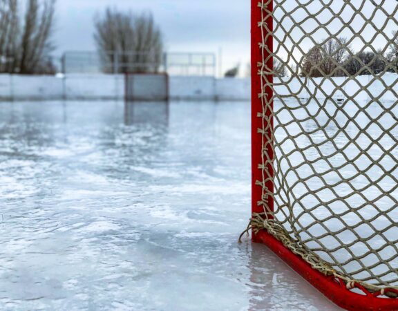 Photograph of a red hockey net on the ice of an outdoor skating rink.