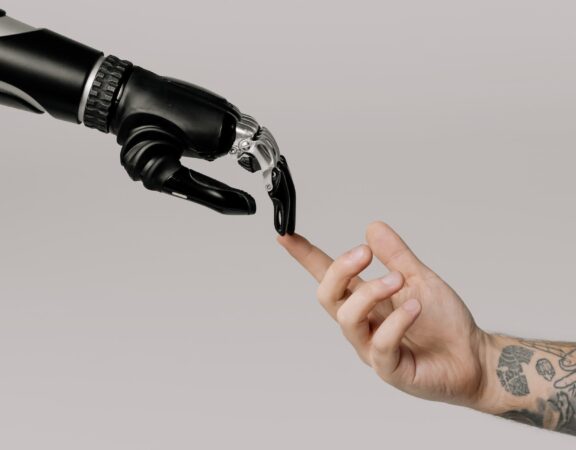 Photograph of a black robotic hand reaching out to touch a human hand