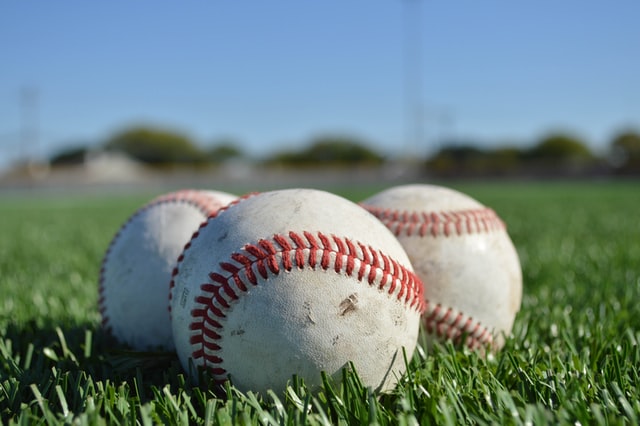 Photograph of three baseballs on the grass, representing three strikes.