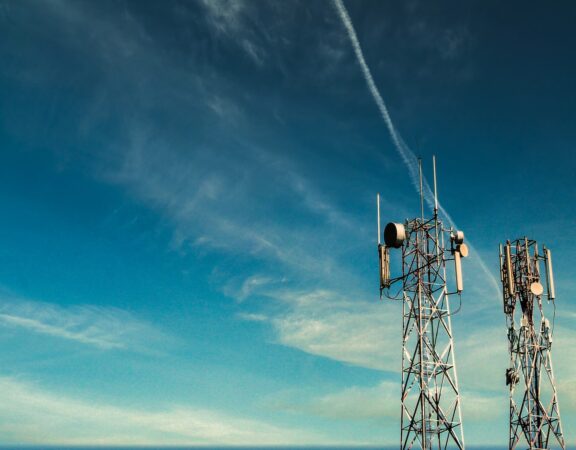 Photograph of two cell towers against a blue sky