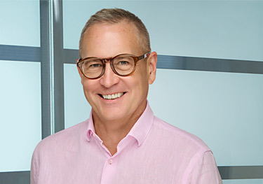 A photograph of registered patent agent David Johnson wearing a pink shirt and glasses.