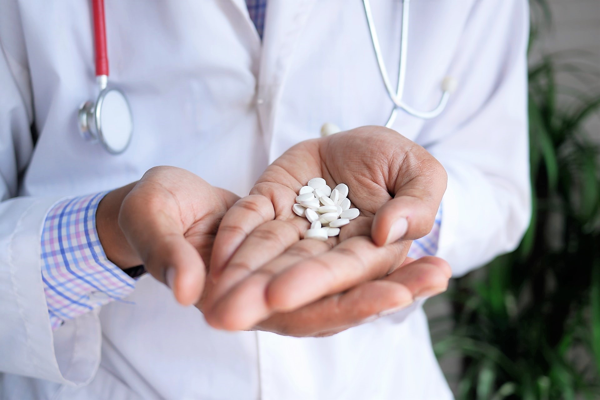 Photograph of a doctor holding out small white pills