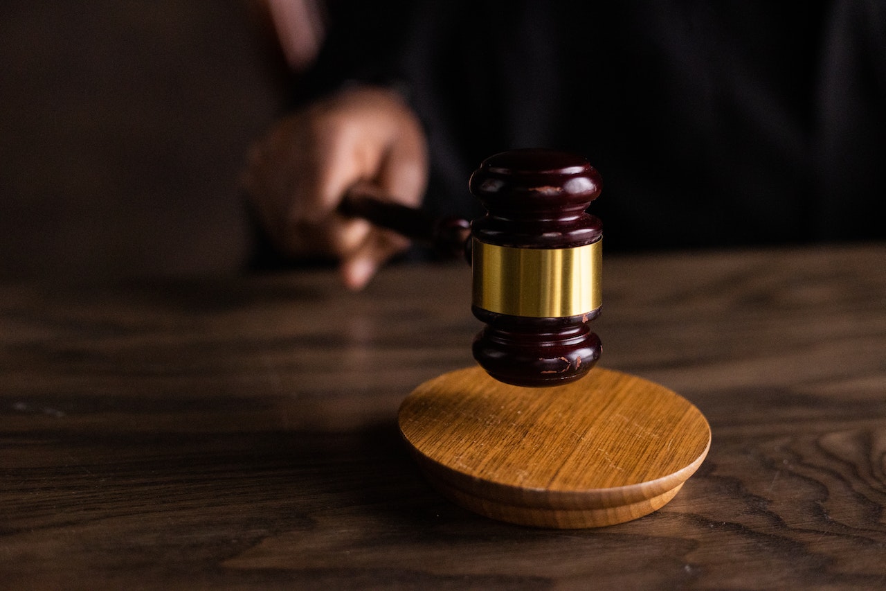 Photograph of a judge knocking a gavel on a wooden block against a dark background