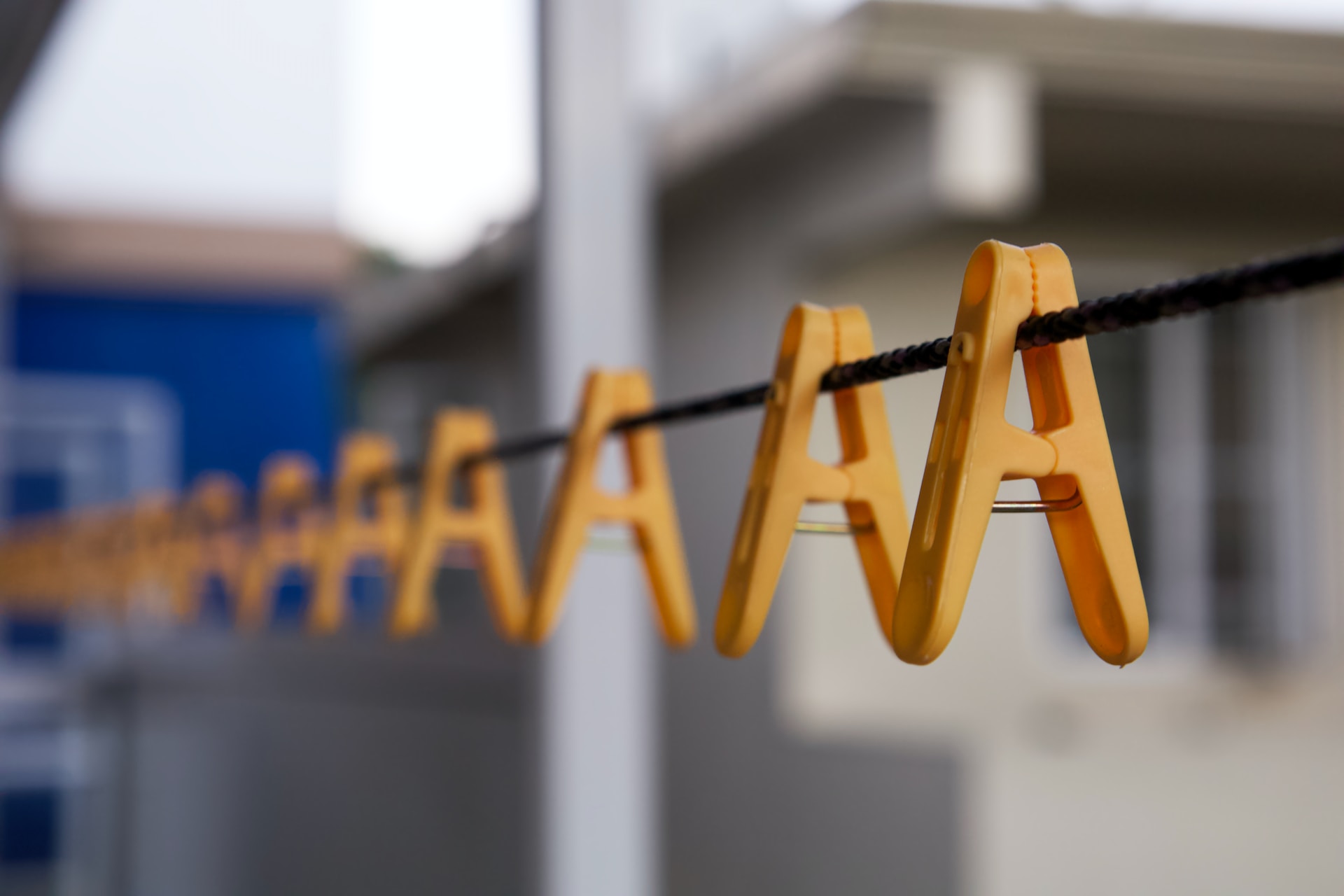 Photograph of clothespins hanging upside down on a clothesline, the clothespins resemble the letter "A".