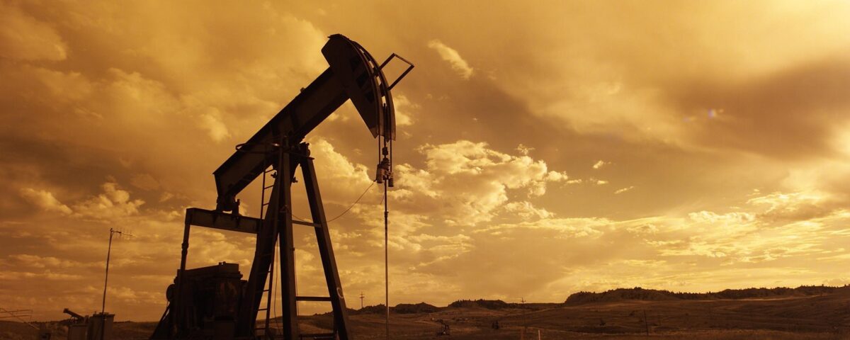 Photograph of a silhouette of a pumpjack in an oil field.