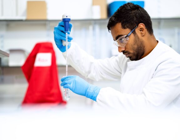 Researcher in a biochemical laboratory pipetting a liquid
