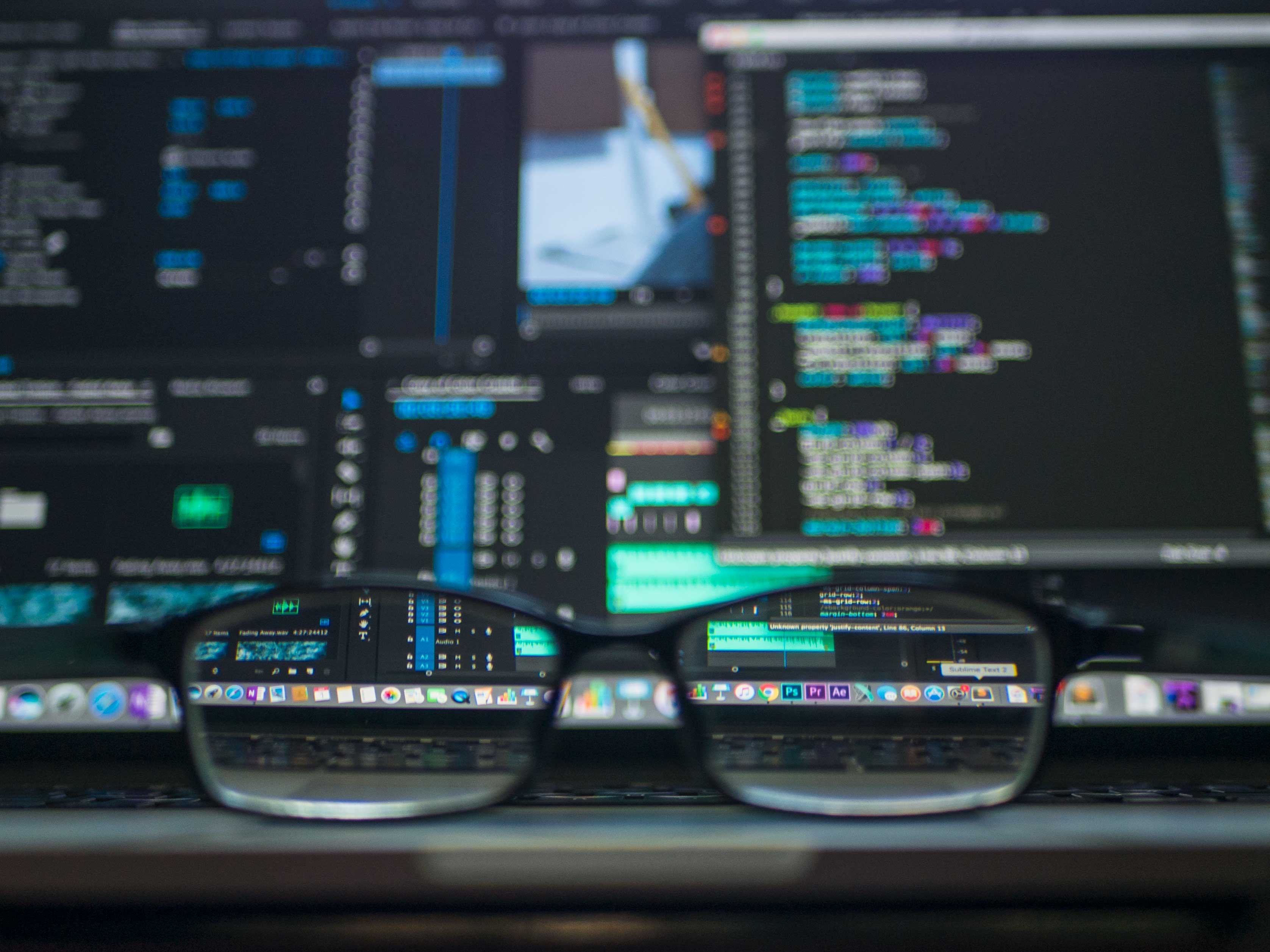 Photograph of eyeglasses focusing on a computer screen displaying software code.