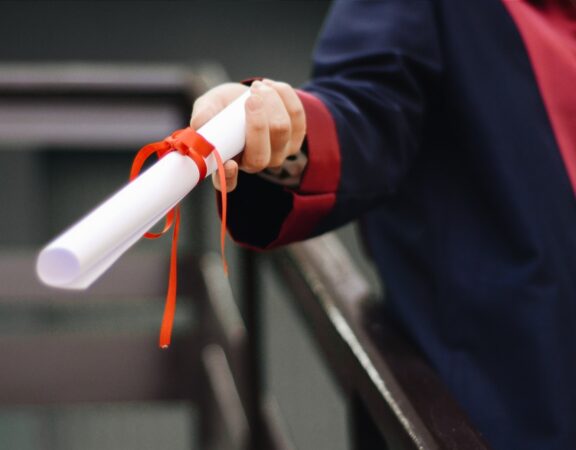 Photograph of a student holding a diploma at a graduation ceremony