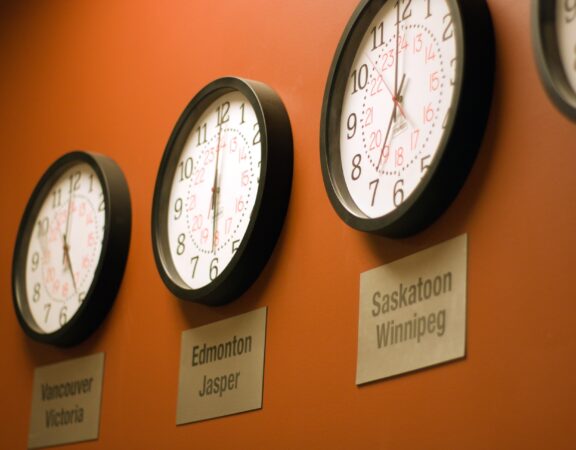 Photograph of several clocks on a wall indicating the time in different time zones.