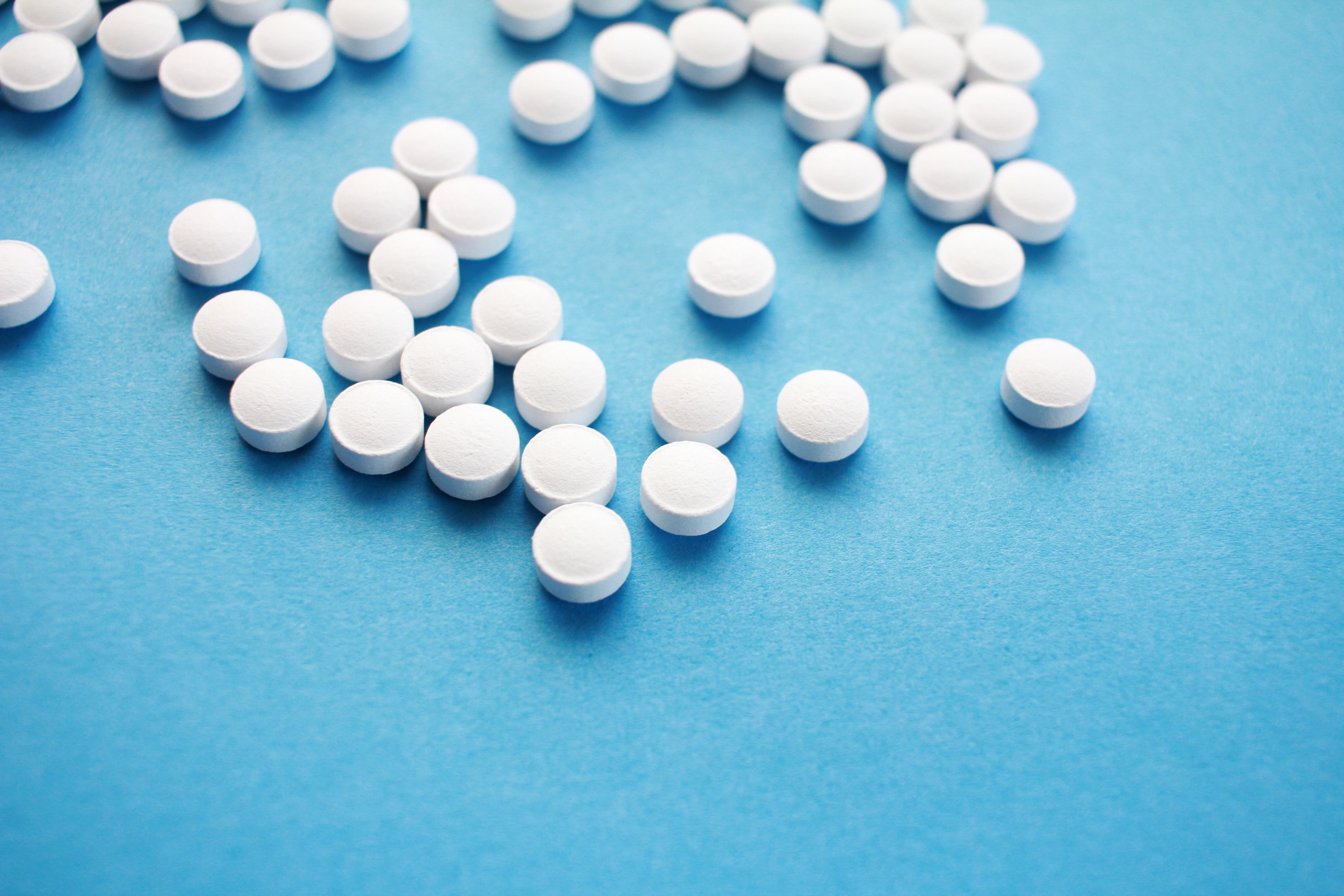 Photograph of white pharmaceutical pills on a blue background.